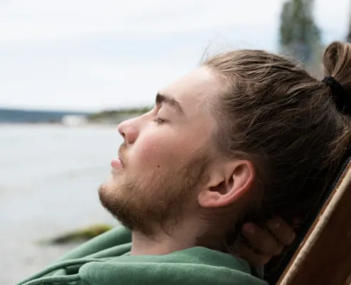 A young man relaxing outside with his eyes closed