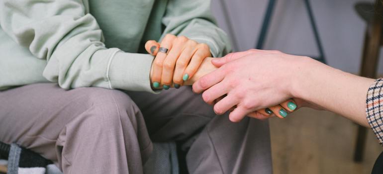 A person holding their loved one’s hand for support