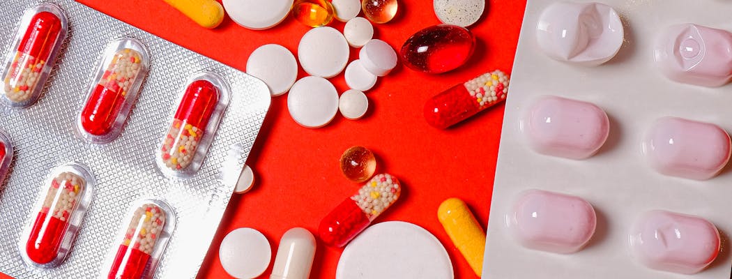 Different types of pills on red background to show how bad is the opioid crisis