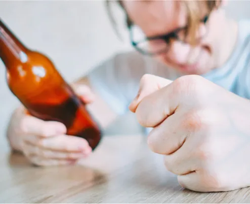 A man at a table, holding a bottle during the Alcohol Awareness Month