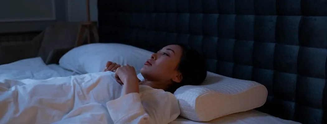 A person lying in the bed, having trouble sleeping
