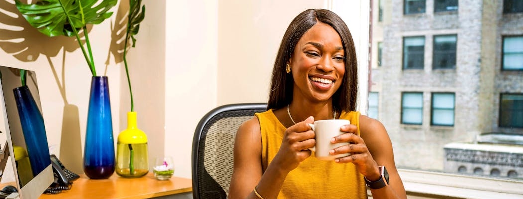 A person feeling happy, drinking coffee in their office